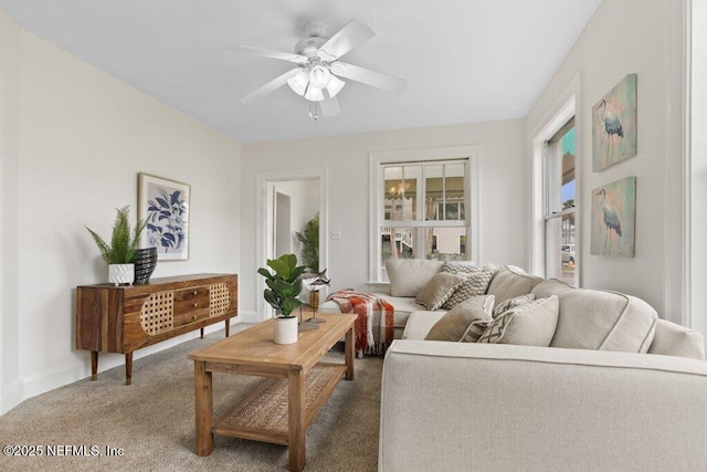 carpeted living area with a ceiling fan and baseboards