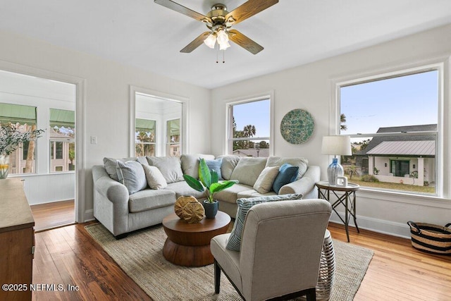 living room featuring ceiling fan, hardwood / wood-style floors, baseboards, and a healthy amount of sunlight