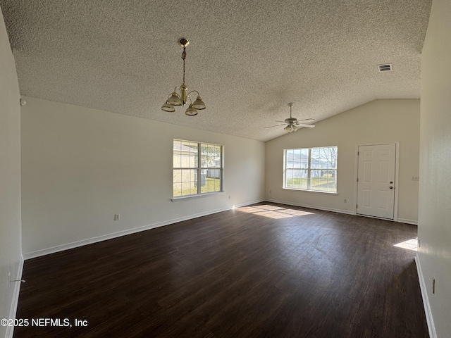 empty room with dark wood-type flooring, ceiling fan with notable chandelier, vaulted ceiling, and a textured ceiling