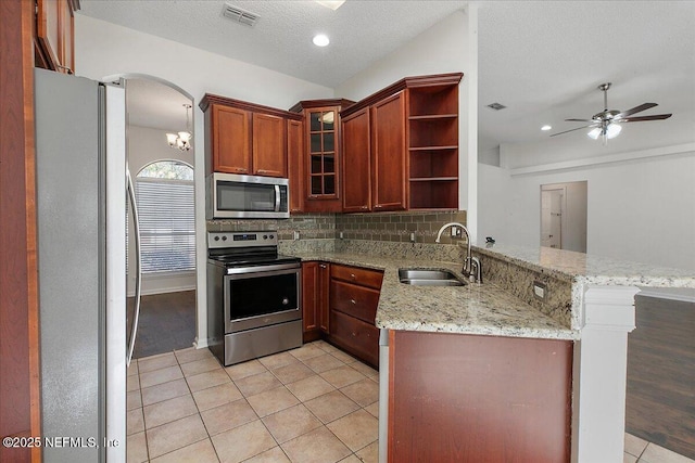 kitchen with light stone countertops, appliances with stainless steel finishes, kitchen peninsula, and light tile patterned flooring