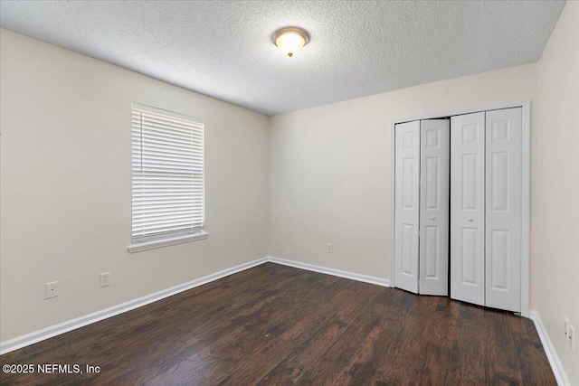 unfurnished bedroom featuring a textured ceiling, a closet, and dark hardwood / wood-style floors