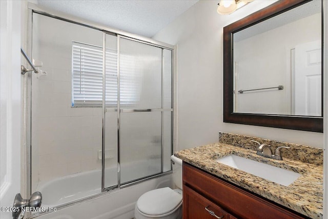 full bathroom with a textured ceiling, enclosed tub / shower combo, vanity, and toilet