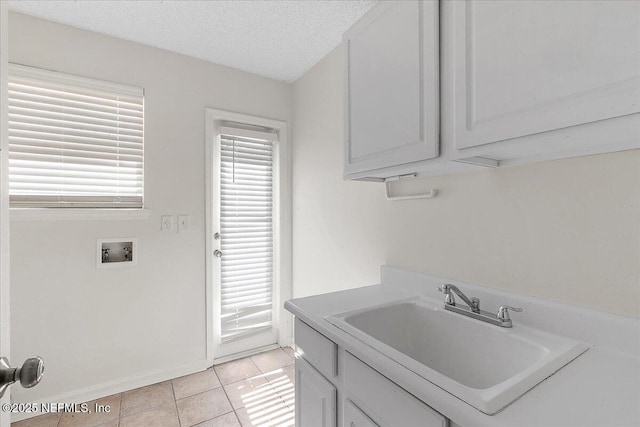 laundry area with sink, light tile patterned floors, cabinets, a textured ceiling, and washer hookup