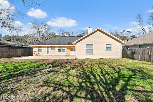 rear view of house featuring a lawn and a patio