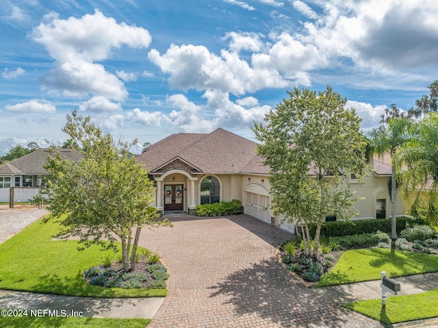 view of front of property featuring a front yard, a garage, and french doors