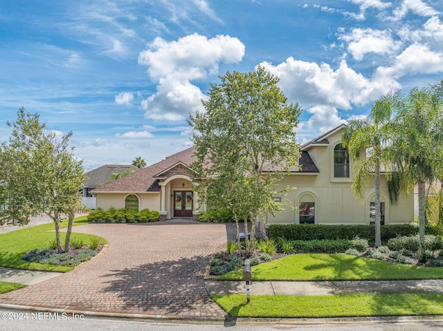 mediterranean / spanish house featuring french doors and a front lawn