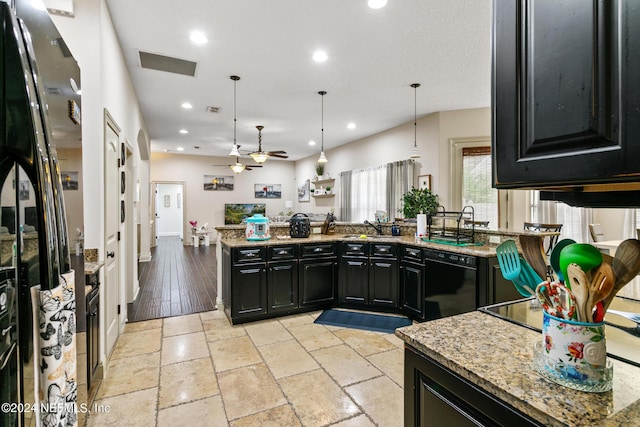 kitchen with ceiling fan, black appliances, hanging light fixtures, and light stone countertops