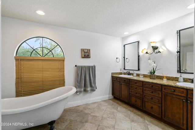 bathroom featuring a textured ceiling, a tub, and vanity