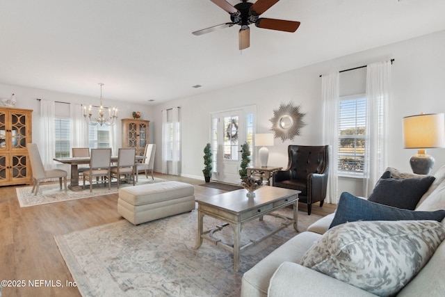 living room with ceiling fan with notable chandelier and light hardwood / wood-style floors