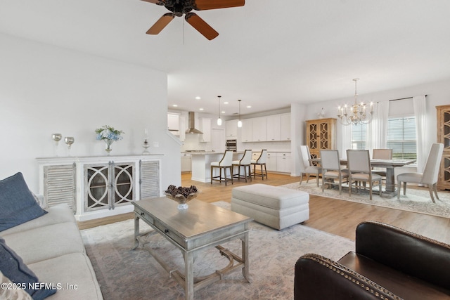 living room featuring light wood-type flooring and ceiling fan with notable chandelier