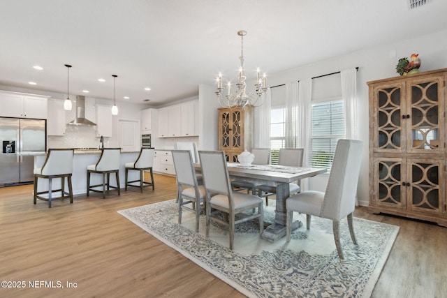 dining space with a chandelier and light hardwood / wood-style floors