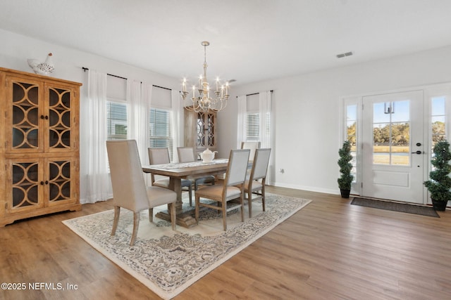 dining space with a notable chandelier, a wealth of natural light, and hardwood / wood-style floors