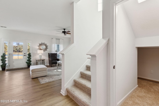 stairway with ceiling fan and wood-type flooring