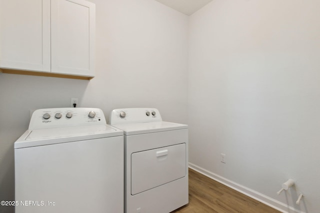 clothes washing area with cabinets, hardwood / wood-style floors, and washer and clothes dryer