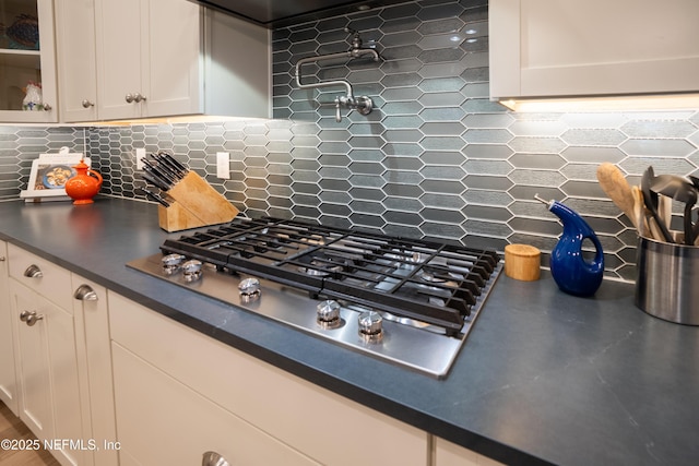 kitchen featuring tasteful backsplash, white cabinets, and stainless steel gas stovetop