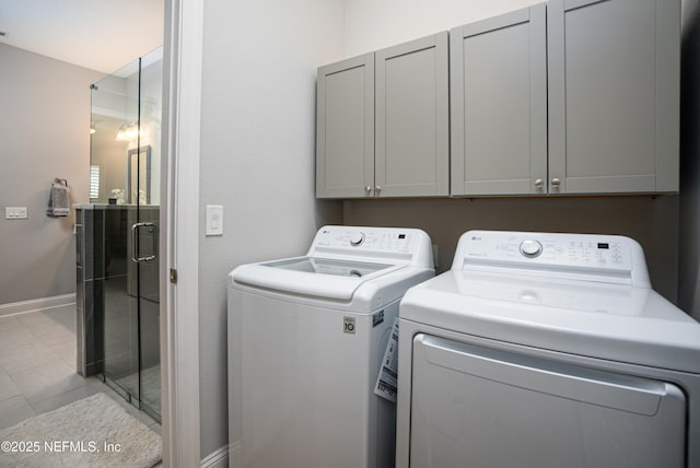 laundry area featuring separate washer and dryer, light tile patterned floors, and cabinets