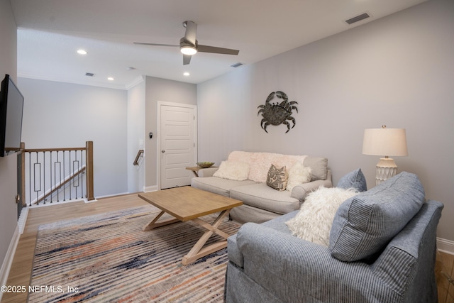 living room featuring hardwood / wood-style flooring, ornamental molding, and ceiling fan