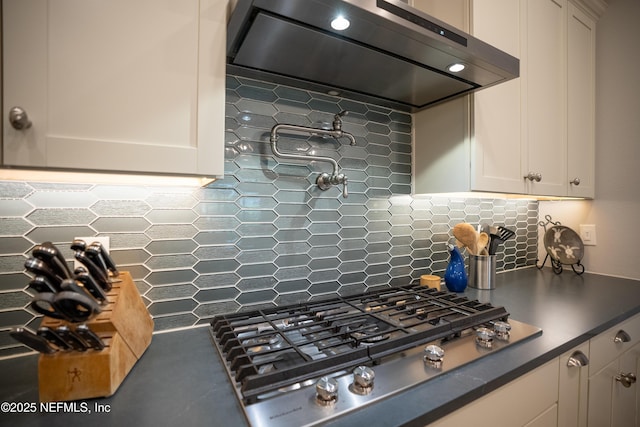 kitchen featuring stainless steel gas stovetop, white cabinetry, decorative backsplash, and range hood