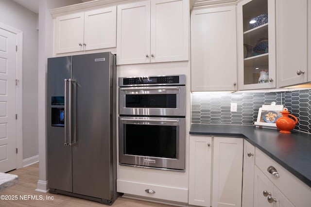 kitchen with tasteful backsplash, white cabinetry, appliances with stainless steel finishes, and light hardwood / wood-style floors