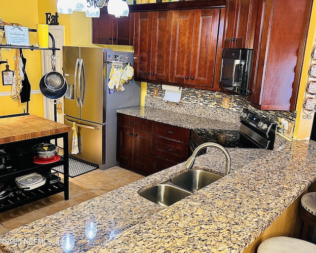 kitchen featuring sink, a breakfast bar, black appliances, and light stone counters