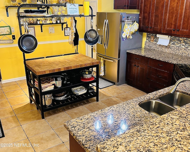 kitchen featuring light stone countertops, an island with sink, appliances with stainless steel finishes, light tile patterned flooring, and sink