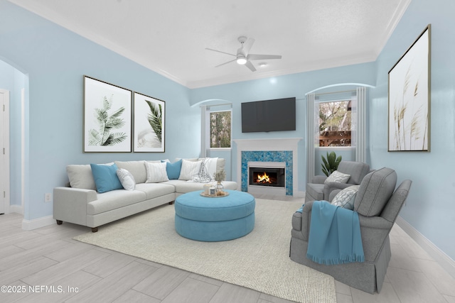 living room with ceiling fan, a high end fireplace, and crown molding