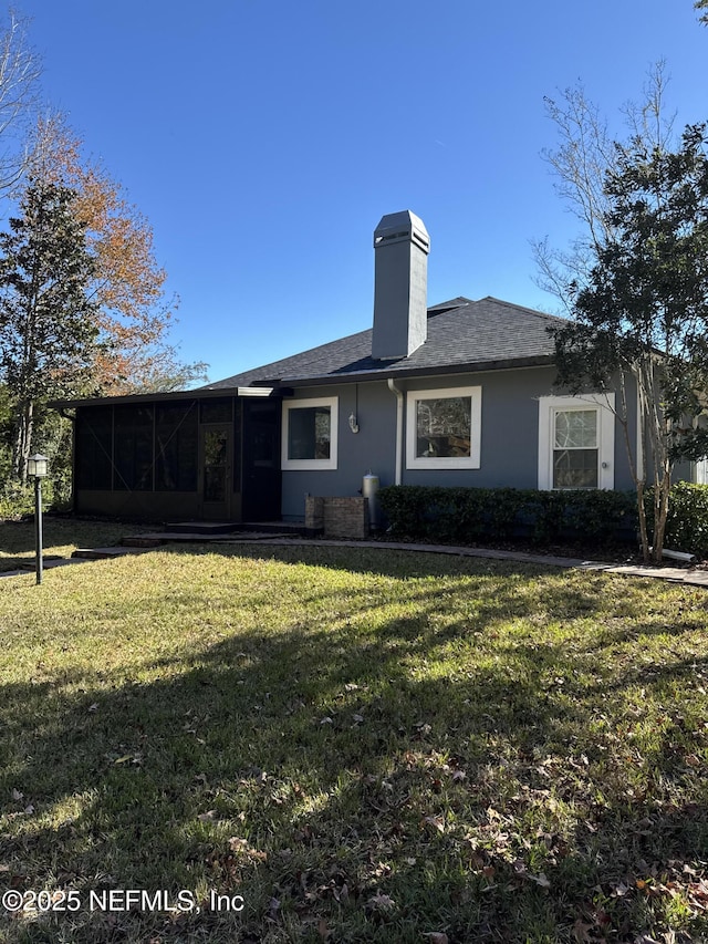 rear view of property featuring a lawn and a sunroom