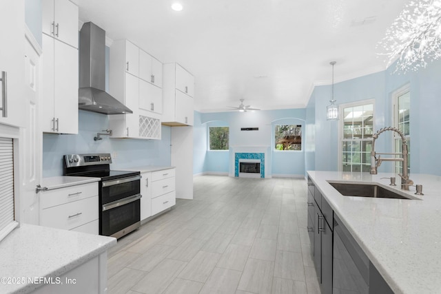 kitchen with pendant lighting, white cabinets, wall chimney range hood, double oven range, and sink