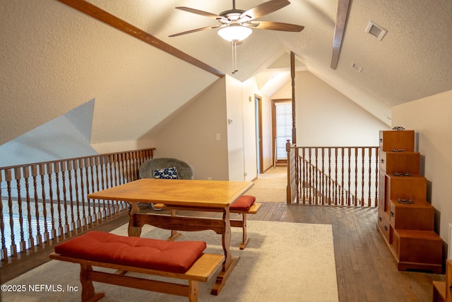 additional living space with vaulted ceiling, a textured ceiling, and hardwood / wood-style flooring