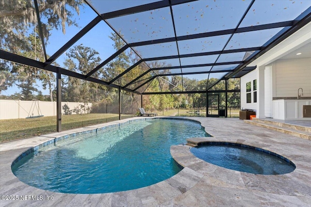 view of pool with a patio area, an in ground hot tub, and glass enclosure