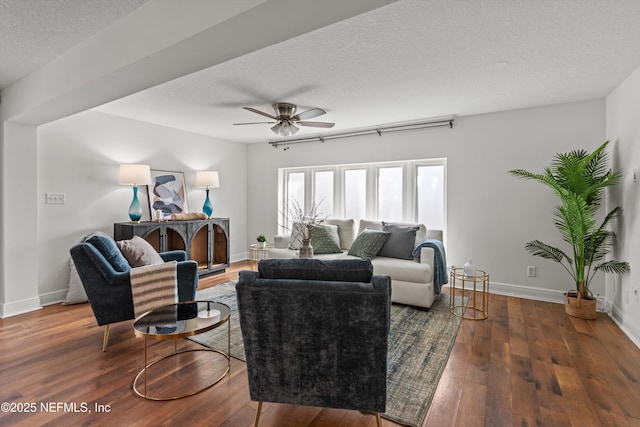 living room with dark wood-type flooring, ceiling fan, and a textured ceiling