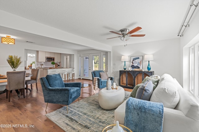 living room with ceiling fan, dark hardwood / wood-style flooring, and a textured ceiling