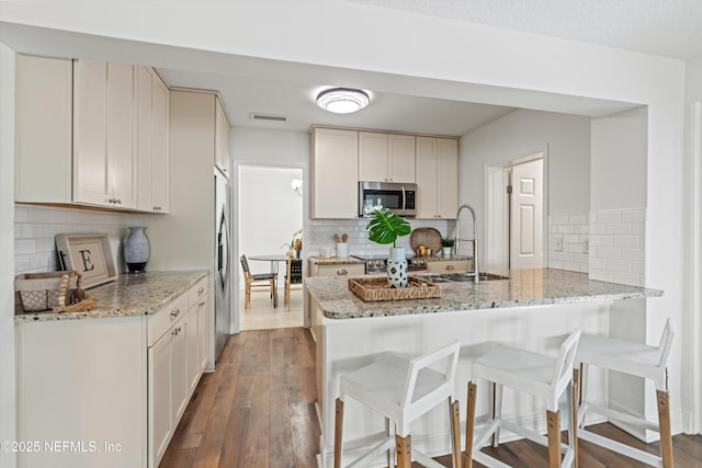 kitchen with sink, white cabinets, light stone counters, and kitchen peninsula