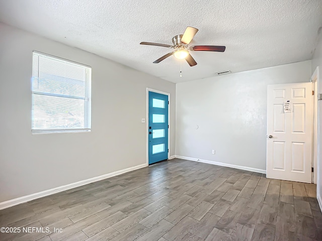 spare room featuring ceiling fan, wood-type flooring, and a textured ceiling