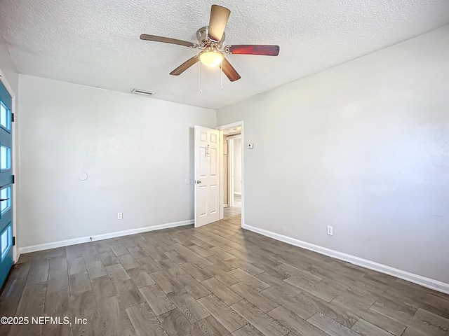 unfurnished room featuring ceiling fan, a textured ceiling, and dark hardwood / wood-style floors