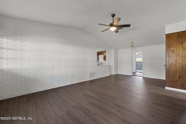 interior space featuring lofted ceiling, brick wall, dark wood-type flooring, and ceiling fan