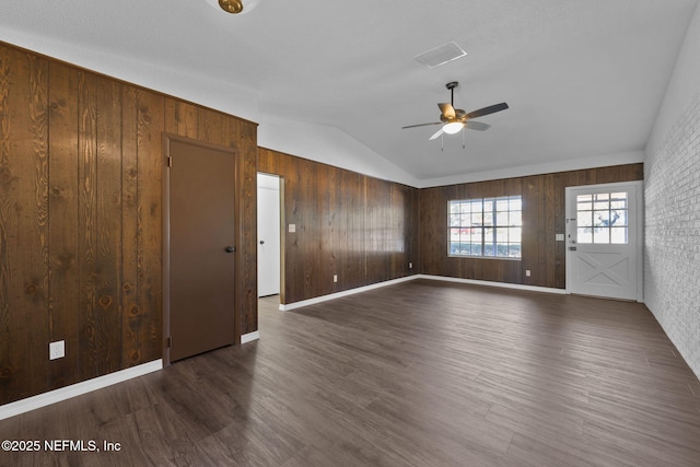 empty room with ceiling fan, dark hardwood / wood-style flooring, wooden walls, and vaulted ceiling