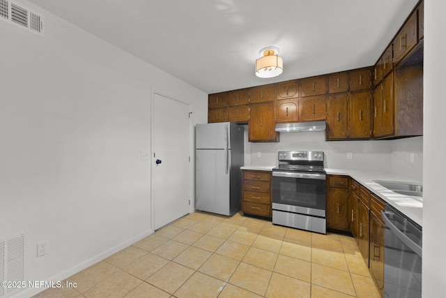 kitchen with sink, dark brown cabinetry, light tile patterned floors, and appliances with stainless steel finishes