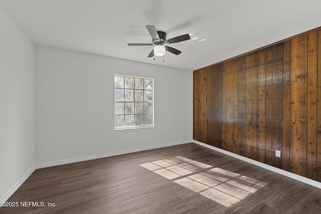 spare room with wooden walls, ceiling fan, and dark hardwood / wood-style floors