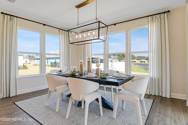 dining space featuring dark wood-style flooring, a healthy amount of sunlight, and baseboards