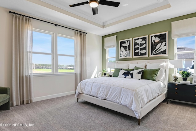 carpeted bedroom with a ceiling fan, a raised ceiling, crown molding, and baseboards