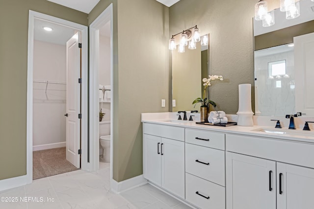 bathroom with toilet, marble finish floor, double vanity, and a sink