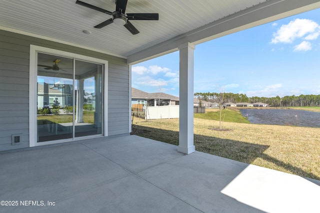 view of patio with ceiling fan, a water view, and fence