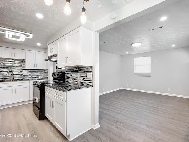 kitchen featuring dark stone countertops, white cabinets, light wood-type flooring, and black range with electric cooktop