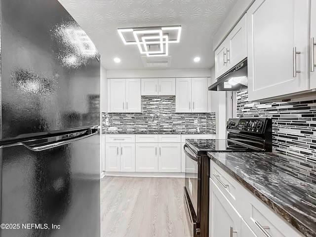 kitchen with black appliances, white cabinetry, dark stone countertops, sink, and light wood-type flooring