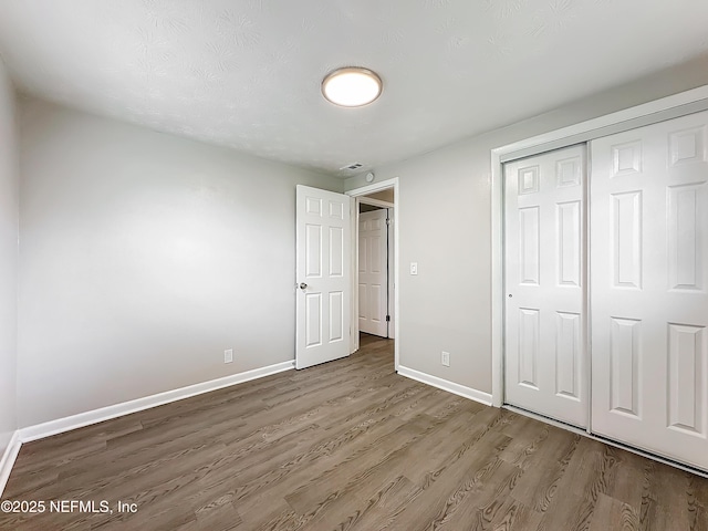 unfurnished bedroom with a closet and hardwood / wood-style flooring