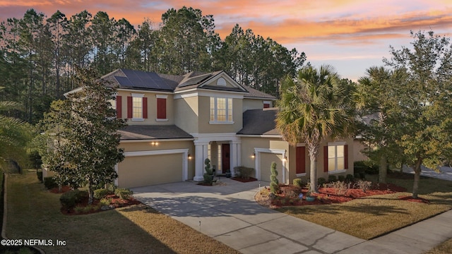 view of front of home featuring a garage, a yard, and solar panels