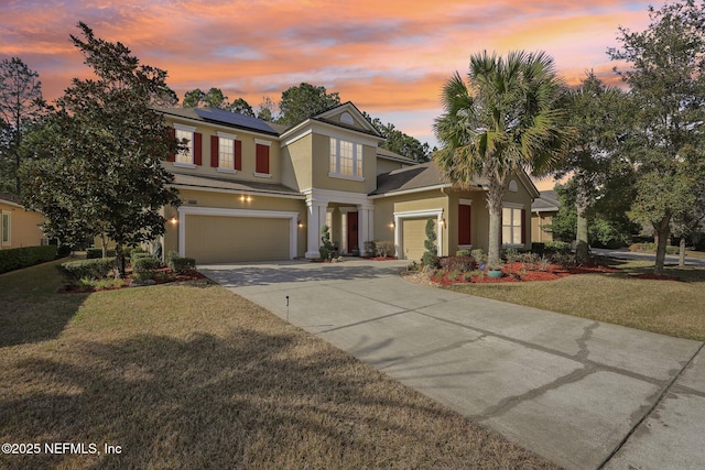 view of front of home featuring a yard, a garage, and solar panels