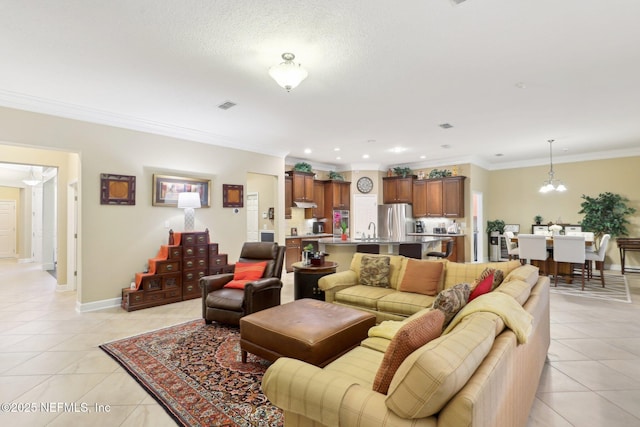 tiled living room featuring ornamental molding, a chandelier, sink, and a textured ceiling