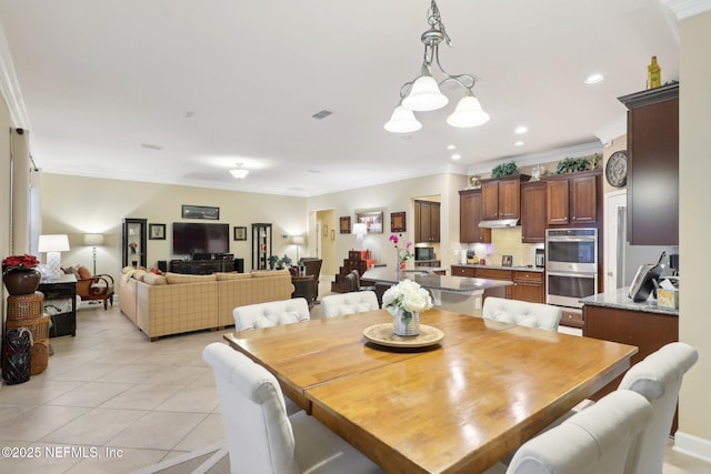 tiled dining area featuring crown molding and an inviting chandelier